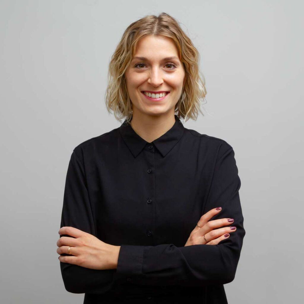 Foto der systemischen Coachin, Steffy Kämmerer, lächelnd vor Fotostudiohintergrund im schwarzen-weißen Outfit.
