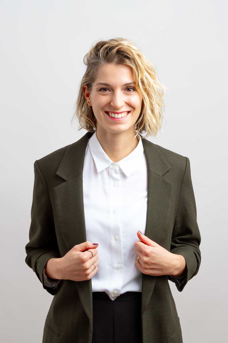 Foto der systemischen Coachin, Steffy Kämmerer, lachend vor Fotostudiohintergrund im duneklgrün-weißen Outfit.